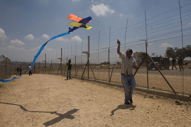 Bassem Abu Rahmah läuft während einer Protestaktion mit einem Drachen entlang der Sperranlange, Bil'in, Westbank, 25. Juli 2008