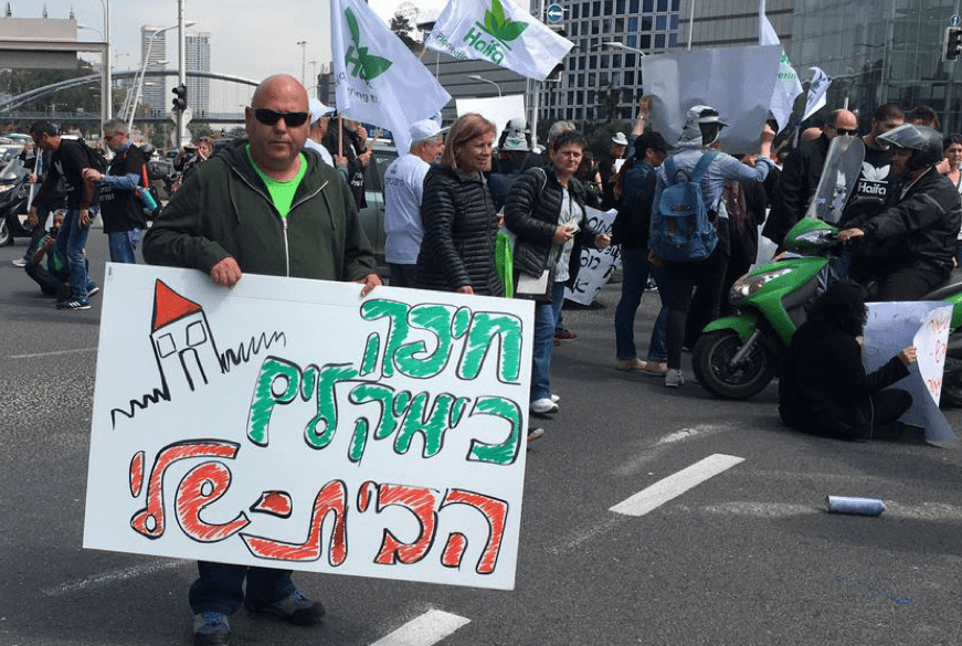 Strassenblockade von Arbeiter*innen gegen die Schließung des Werks. (Auf dem Schild steht: "Haifa Chemicals ist mein Zuhause"), Tel Aviv 2017.