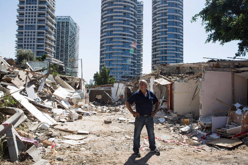 Caduri Halif steht zwischen den Trümmern seines von den israelischen Behörden zerstören Hauses im Givat Amal Viertel im Norden von Tel Aviv, 18. September 2014. Von den Zwangsräumungen waren 20 Menschen betroffen, die nun ohne Obdach und ohne Kompensationen oder Wohnalternativen dahstehen. Die Bewohner, die vom Staat Israel 1947 dort angesiedelt worden waren, haben einen langen Kampf für die Annerkennung ihrer Rechte und Wohnungen geführt, die 1970 privatisert und an Investoren verkauft wurden. (Foto: Activestills)